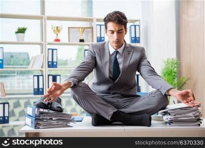 Businessman sitting on top of desk in office