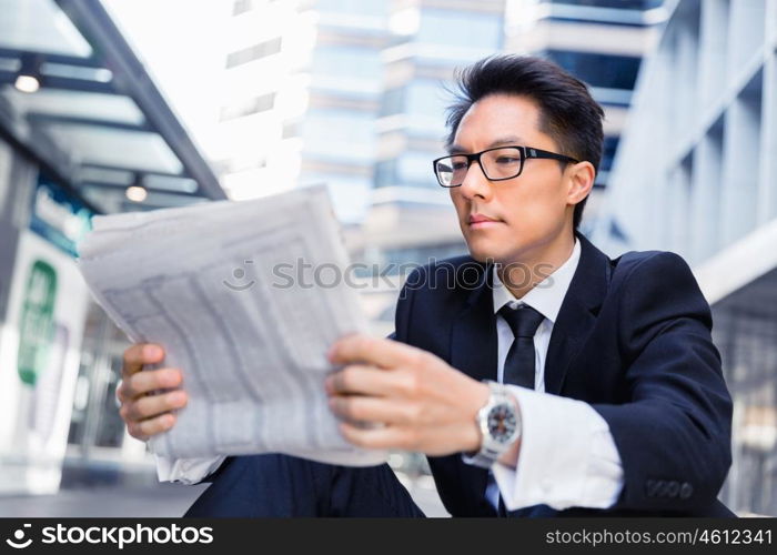 Businessman sitting outdoors with newspaper. First news in the morning