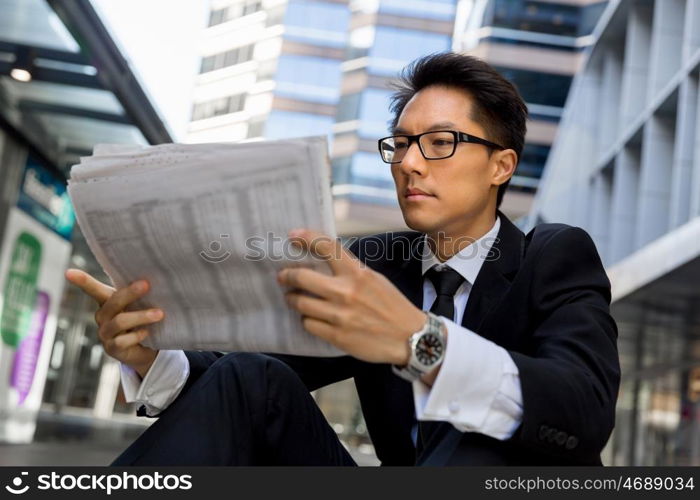 Businessman sitting outdoors with newspaper. First news in the morning