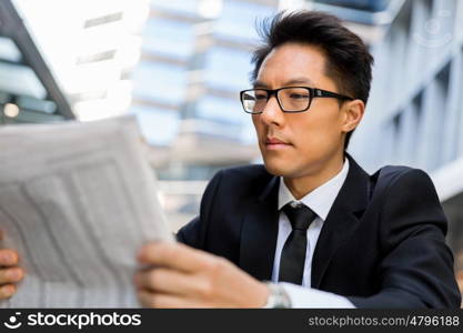 Businessman sitting outdoors with newspaper. First news in the morning