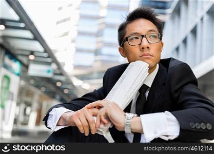 Businessman sitting outdoors with newspaper. Thinking new strategy for his business