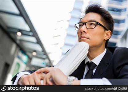Businessman sitting outdoors with newspaper. Thinking new strategy for his business