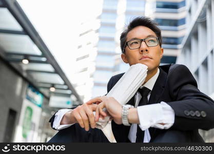 Businessman sitting outdoors with newspaper. Thinking new strategy for his business