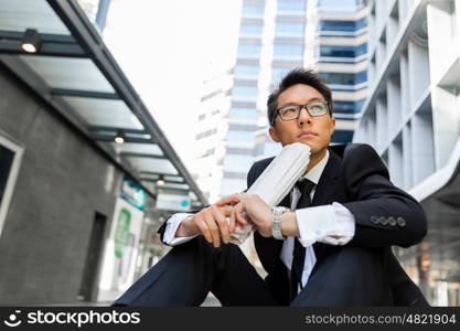 Businessman sitting outdoors with newspaper. Thinking new strategy for his business