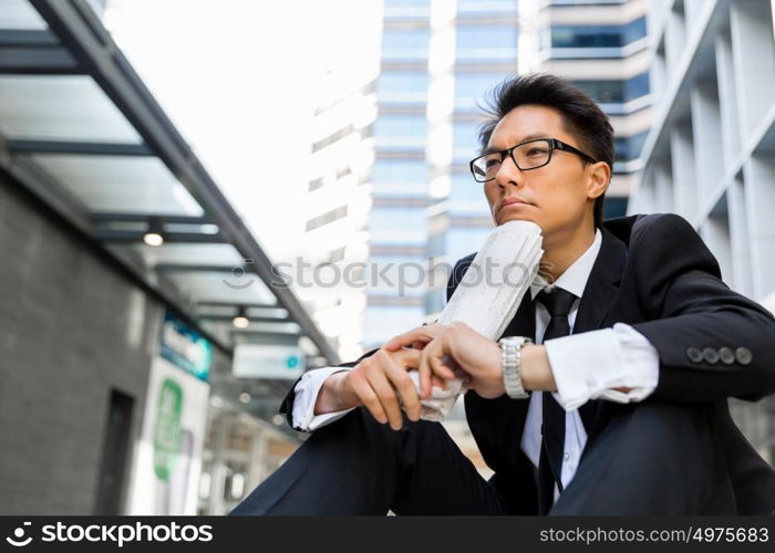 Businessman sitting outdoors with newspaper. Thinking new strategy for his business