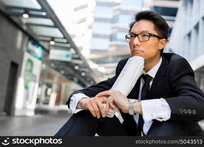 Businessman sitting outdoors with newspaper. Thinking new strategy for his business