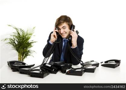 Businessman sitting with a bunch telephones on his front