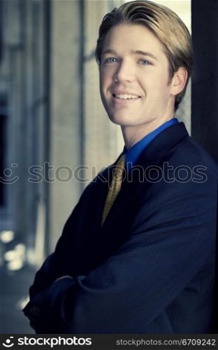 Businessman smiles and stands against the wall