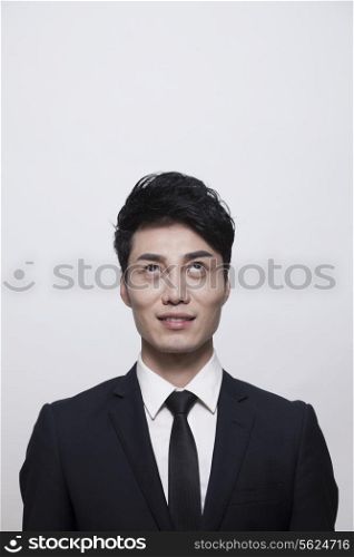 Businessman smiling and looking up, studio shot