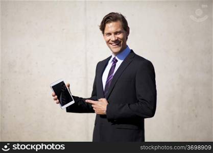 Businessman smiling and pointing at tablet showing something to the viewer