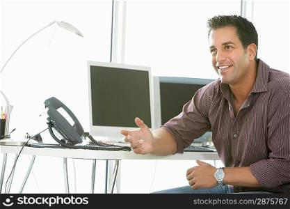 Businessman smiling by computers in office