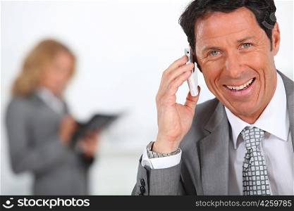 Businessman smiling holding mobile telephone