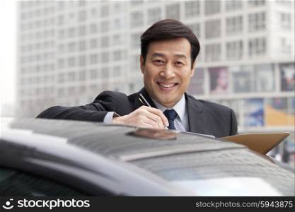 Businessman smiling, working outdoors on car