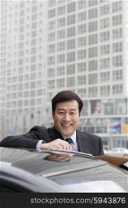 Businessman smiling, working outdoors on car