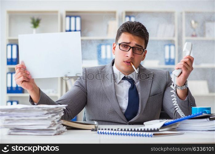 Businessman smoking at work in office holding a blank message bo. Businessman smoking at work in office holding a blank message board