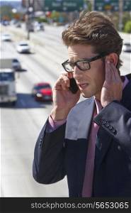 Businessman Speaking On Mobile Phone By Noisy Freeway