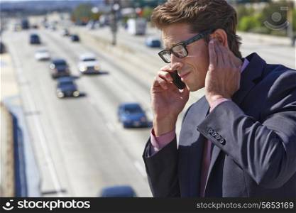 Businessman Speaking On Mobile Phone By Noisy Freeway