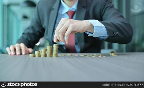 Businessman Stacking Coins in Increasing Order at desk