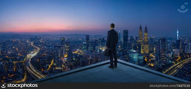 Businessman stand at rooftop looking great cityscape view and thinking business plan of the future . Night scene .