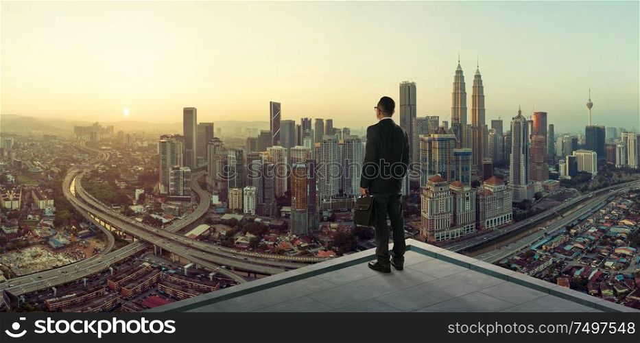 Businessman stand at rooftop looking great cityscape view and thinking business plan of the future .