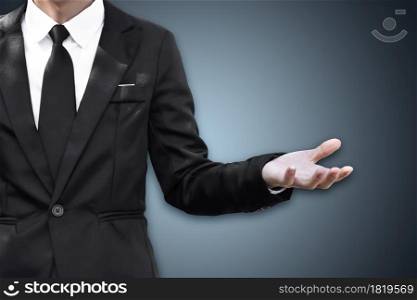 Businessman standing and shows outstretched hand with open palm, copy space.