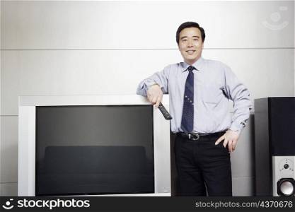 Businessman standing beside a television smiling