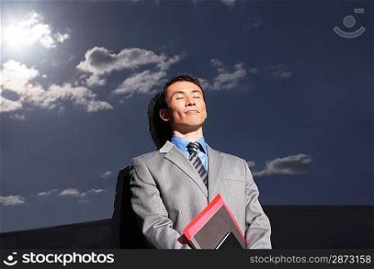 Businessman Standing Beside Building Enjoying Sunshine