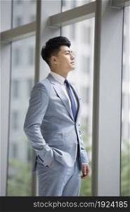 Businessman standing by the window and looking out