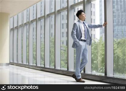 Businessman standing by the window and looking out