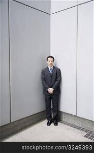 Businessman standing in a corner with his hands clasped