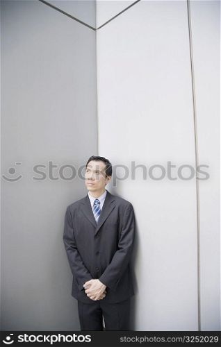 Businessman standing in a corner with his hands clasped