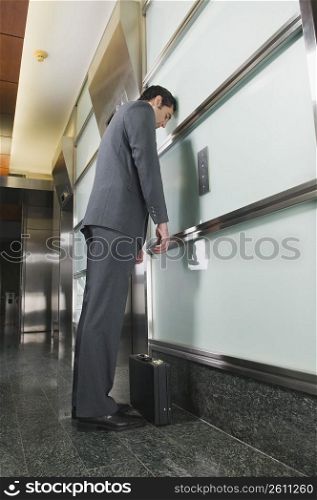 Businessman standing in a corridor and looking tired