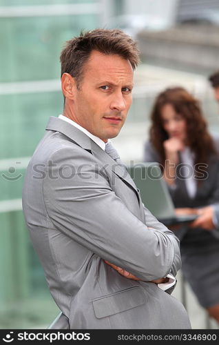 Businessman standing in front of offices outside