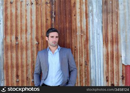 Businessman standing in front of sheet metal wall