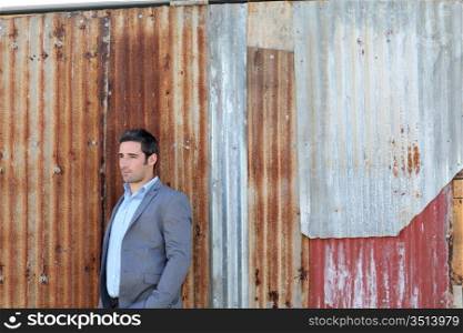 Businessman standing in front of sheet metal wall