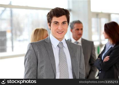 Businessman standing in hall in front of group of business people