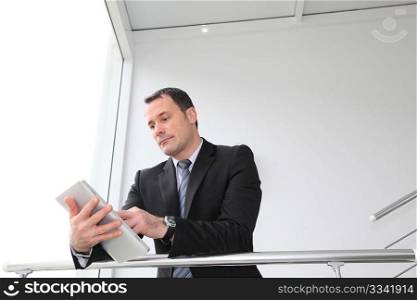 Businessman standing in hall with electronic tablet