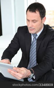 Businessman standing in hall with electronic tablet