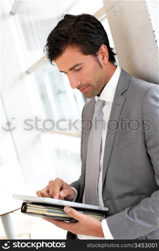 Businessman standing in hall with electronic tablet