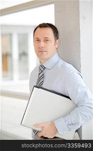 Businessman standing in hall with laptop computer