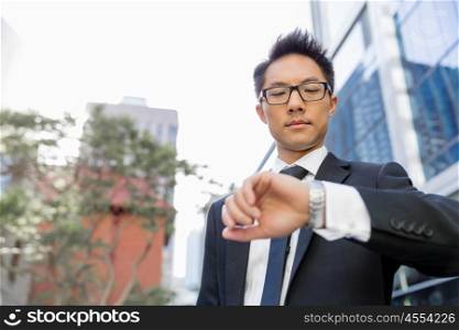 Businessman standing in street and looking at his watch. I need to be in time