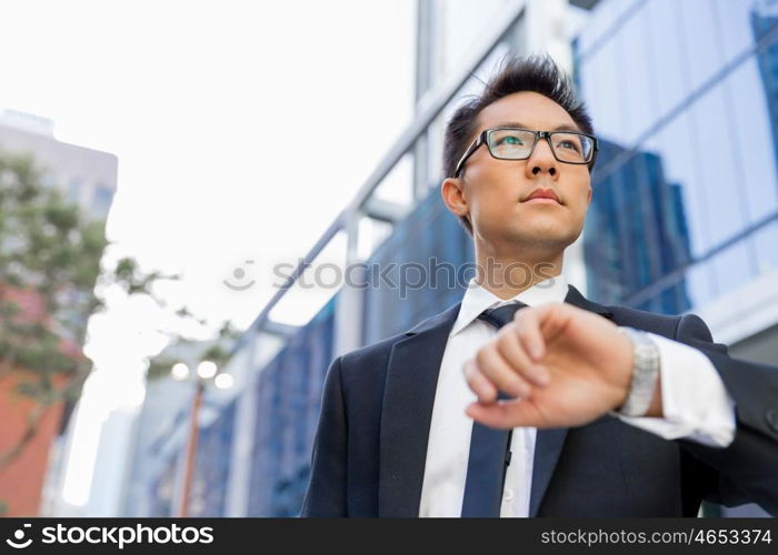 Businessman standing in street and looking at his watch. I need to be in time