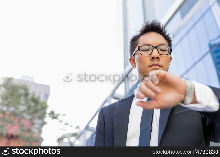 Businessman standing in street and looking at his watch. I need to be in time