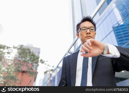 Businessman standing in street and looking at his watch. I need to be in time