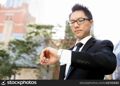 Businessman standing in street and looking at his watch. I need to be in time