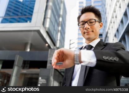 Businessman standing in street and looking at his watch. I need to be in time