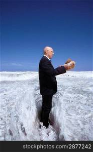 Businessman Standing in the Ocean Reading the Newspaper