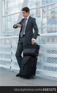 Businessman standing in urban environment of airport with suitcase