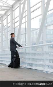 Businessman standing in urban environment of airport with suitcase