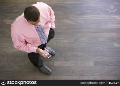 Businessman standing indoors looking at cellular phone